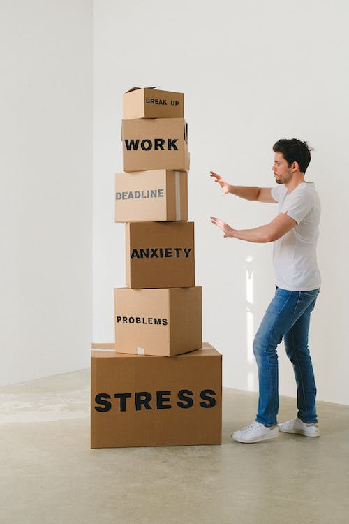 Man standing near carton boxes with various stress-related words