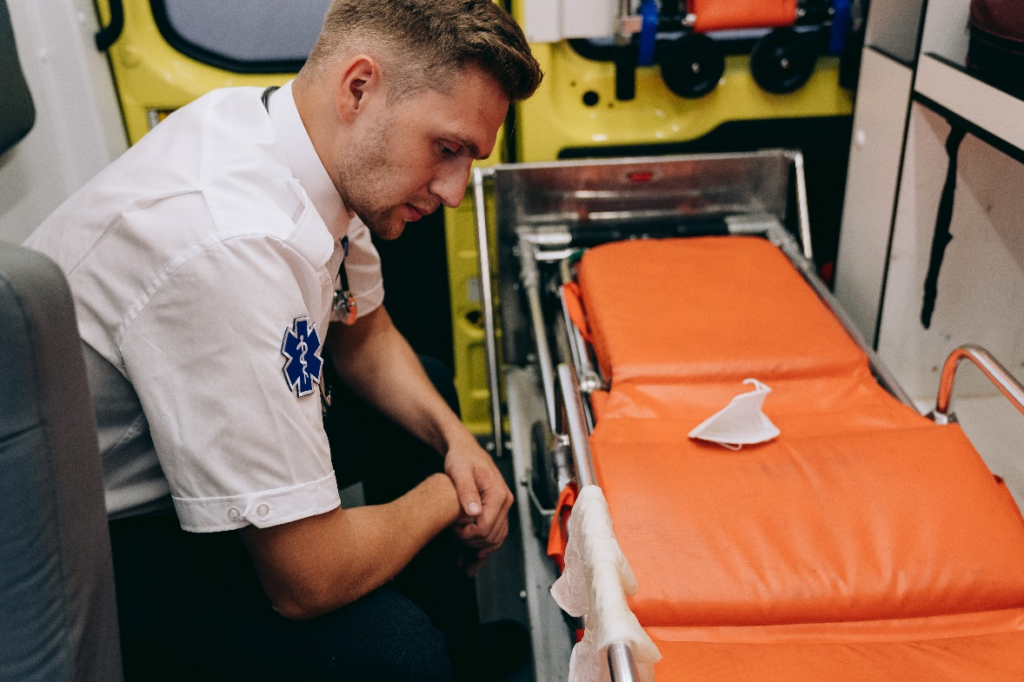 A first responder sitting in front of a stretcher