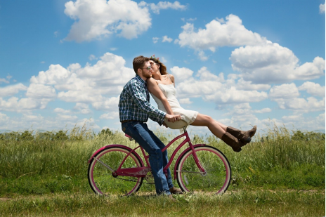 A couple riding a bicycle in the fields 