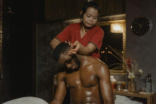 an Asian masseuse massaging a man’s neck