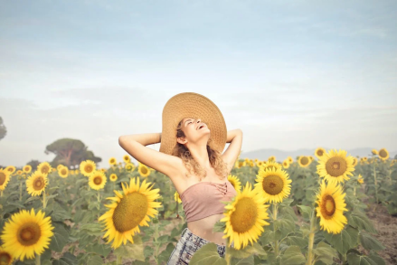 An image of a woman posing while standing in a field of sunflowers