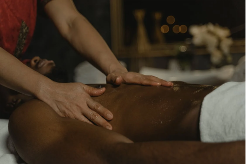 An image of a woman’s hands massaging a male’s body 