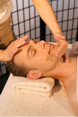 An image of a man in an illuminated room getting a relaxing face massage
