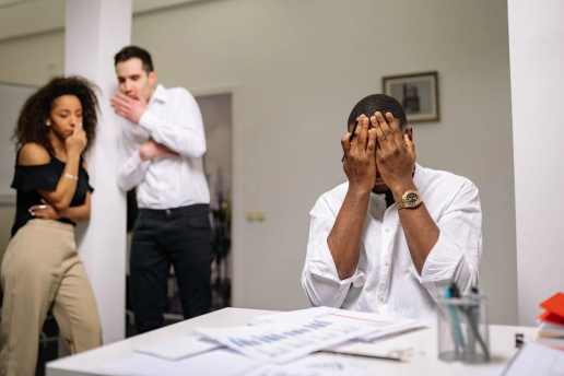 An image of a man with his head in his hands while people look at him from afar 