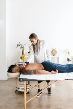 An image of a man lying face down on a massage bed while a woman is doing massage therapy on his back 