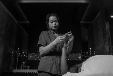 A gray scale image of a female massage therapist massaging a person’s hands
