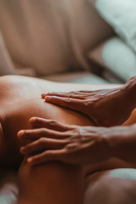 An image of a female massage therapist massaging a person’s bare back with their hands 