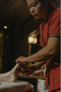 An image of a massage therapist massaging a client’s foot with their hands 