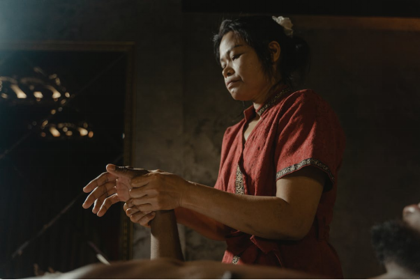 A traditional Asian massage therapist massaging a person’s hand