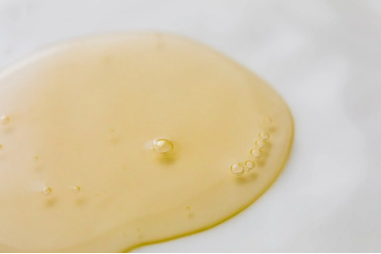 An image of transparent yellowish massage oil on white surface
